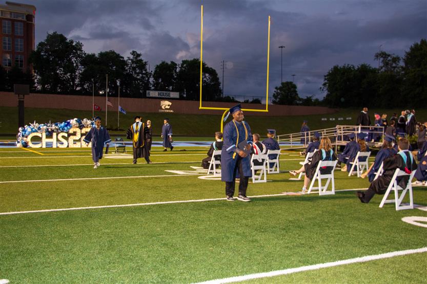 Students graduate outside on a football field